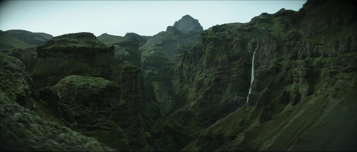 A waterfall flows down a mountain range