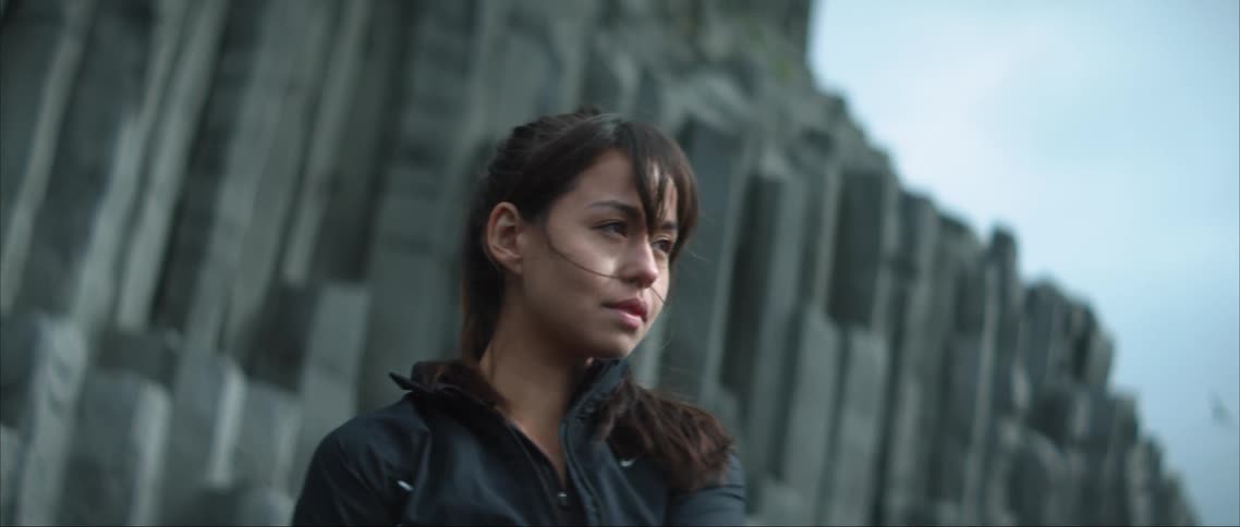 A woman standing stretching in front of a rock face