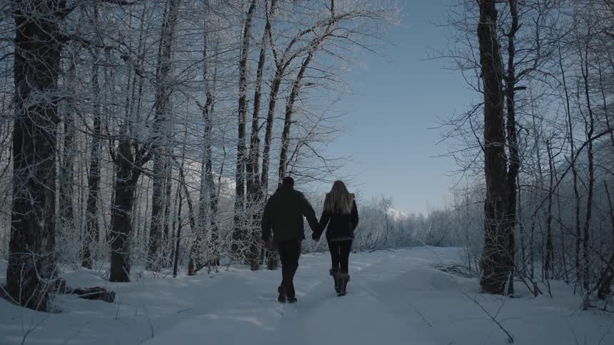 Couple walking a snowy path while holding hands