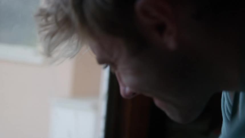 A man is standing inside near a window scrubbing a countertop