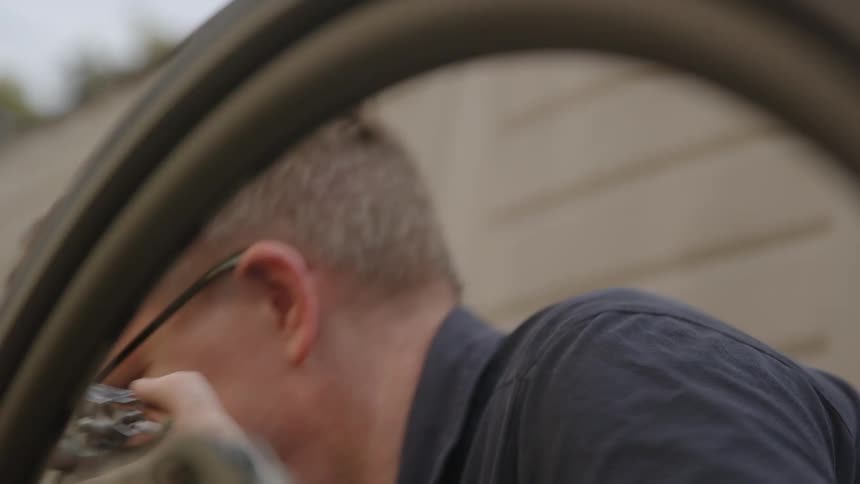 A man rotating a bicycle tire while making repairs