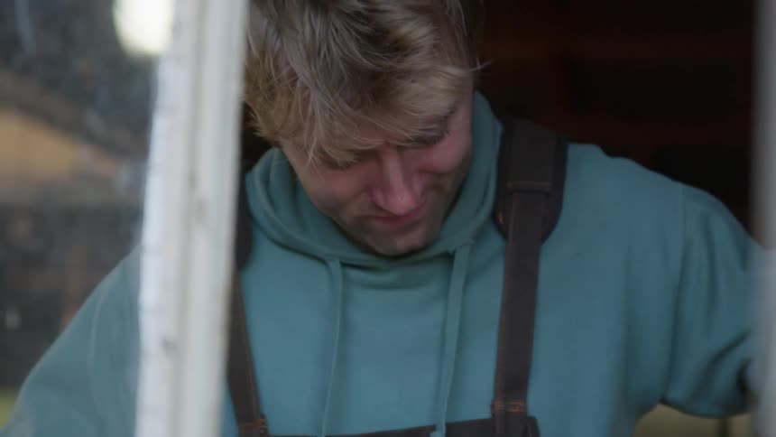 A blonde man in a hoodie and coveralls