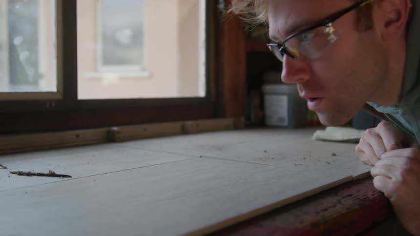 Carpenter working in workshop blows dust off board