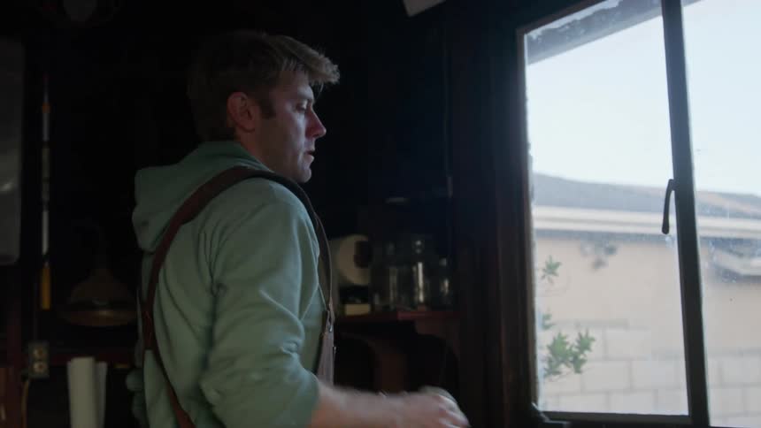 A man is closing a window in a house