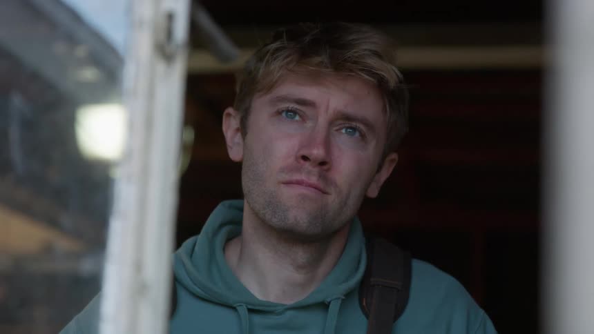 Man working in workshop looks out open window sadly
