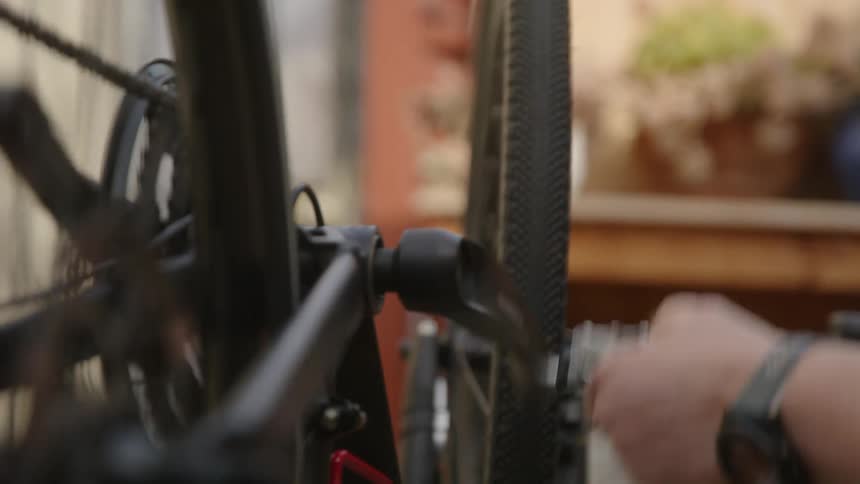 Man manually rotates pedals on bicycle while examining it