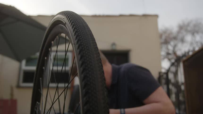 A man fixing a bicycle upside down outside