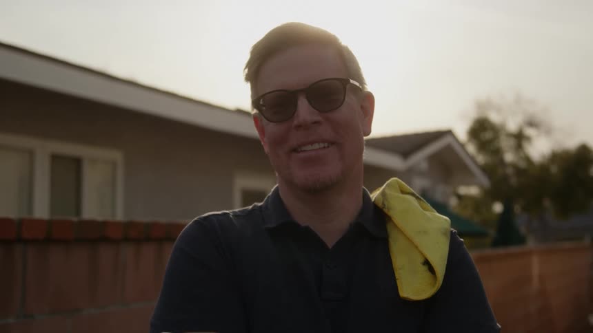 A man is smiling in his backyard