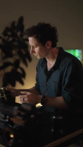 Man with dark shirt looks at camera lens and types on laptop