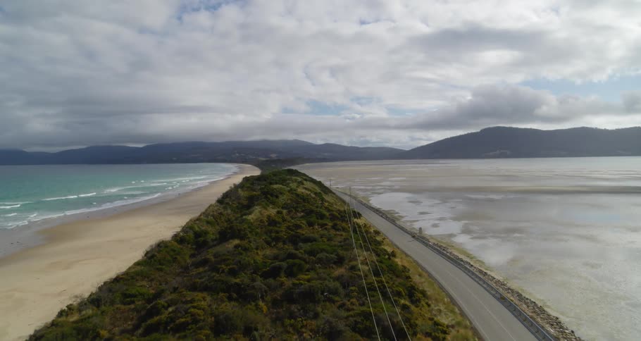 An aerial view of a beach coastline and a road that travels alongside it