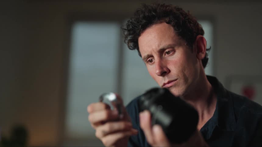Man sitting at desk and examining a camera lens