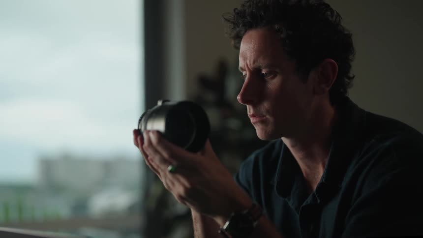 A man is examining a camera lens