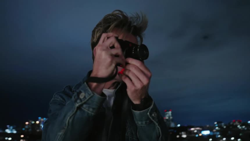 A man is taking pictures while standing outdoors at night