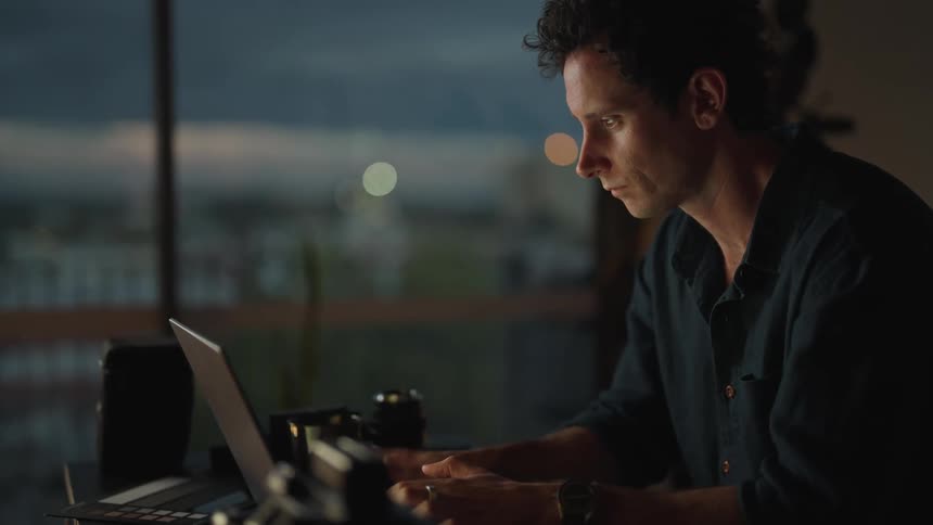 A man is sitting in front of his laptop and looks stressed