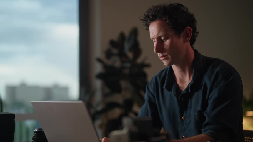 A man drinks coffee while using his laptop