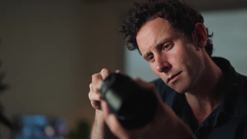 A man holding a camera lens and using a tool on it