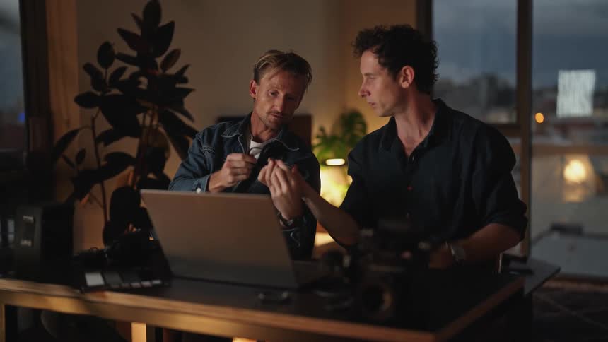Two friends are talking together and sitting at a desk