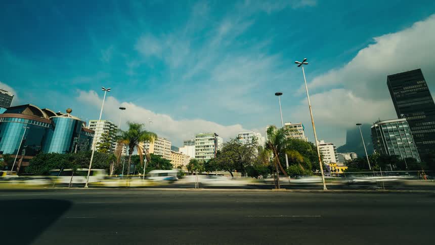 A timelapse of traffic on a road with a city skyline in the background