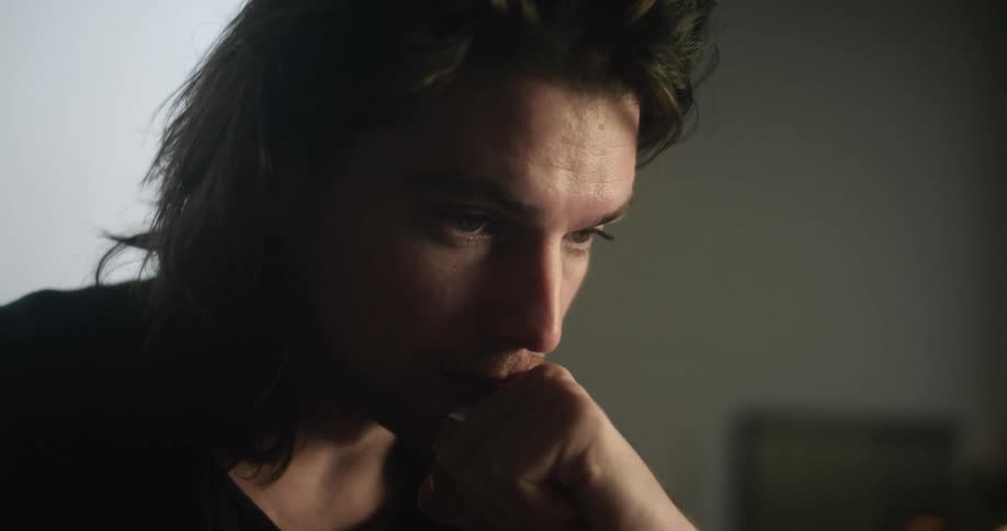 A man is sitting indoors and is thinking about something