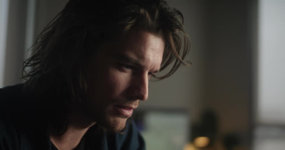 A close up of a mans face looking contemplatively and putting his hand on his chin and face