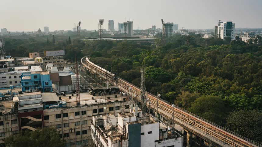 A time lapse of a city shows cars and a train traveling amidst trees and buildings