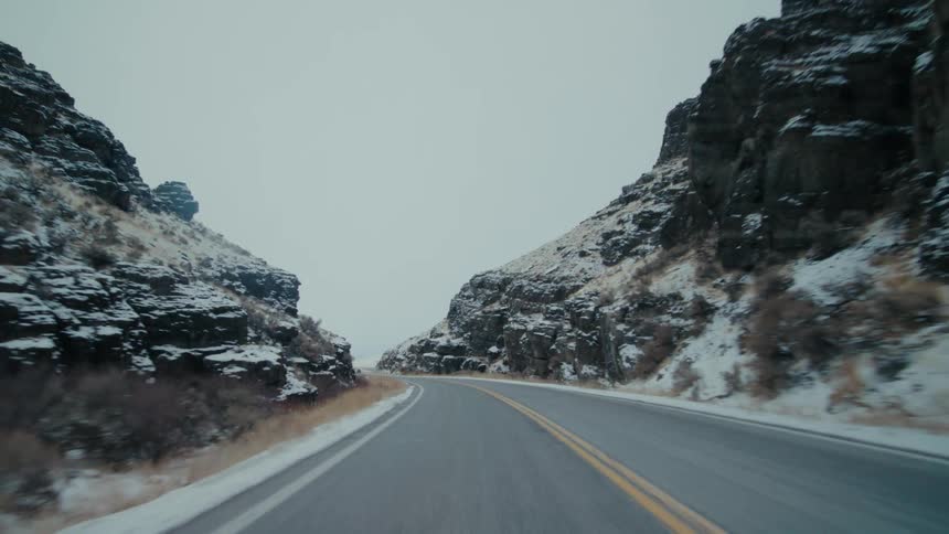 Pickup truck drives along highway between snow covered hills