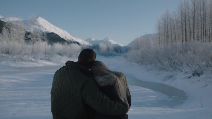 A man and woman hug on an icy pond