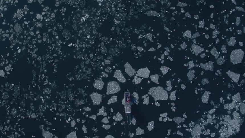 A boat is sailing in the ice below