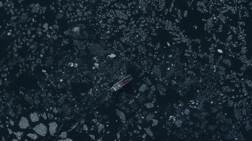 A boat sails in the ice of the water below
