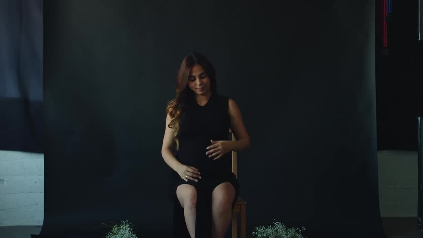 A portrait of a pregnant woman sitting down in a chair