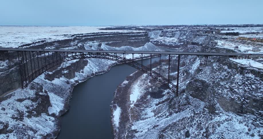 A bridge over a canyon and river flowing under it with traffic traveling on the bridge