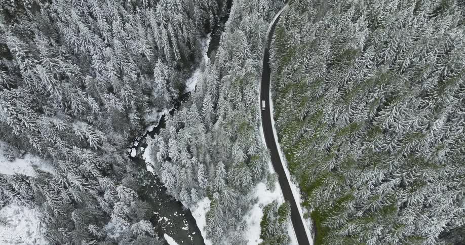 Aerial view of a car driving on a road during winter