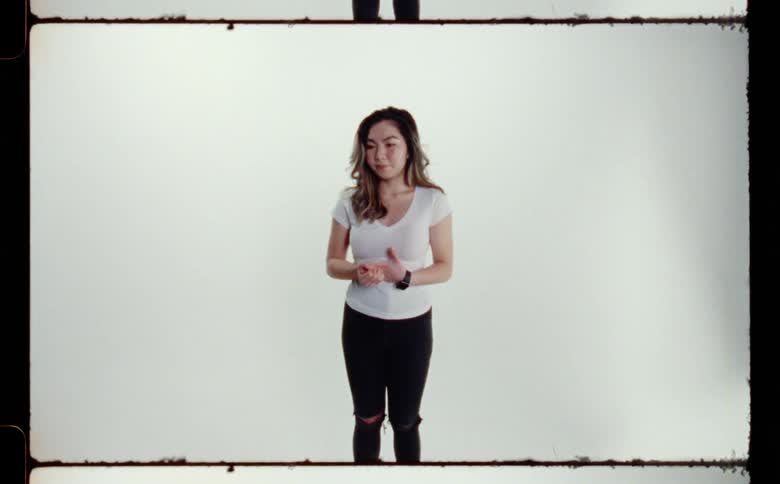A sad looking woman fidgeting in front of a white background