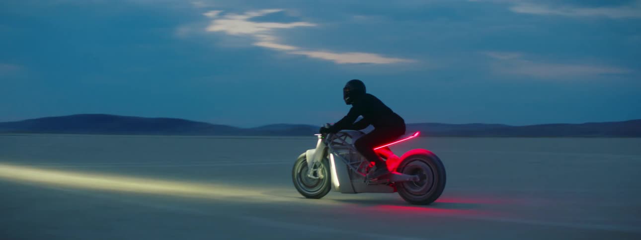 A man rides his motorcycle through a flat desert