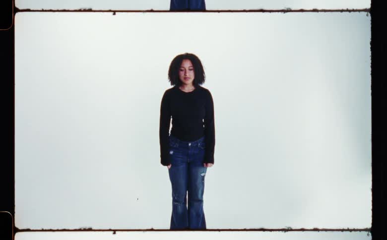Woman stands straight posing against white and black backdrop