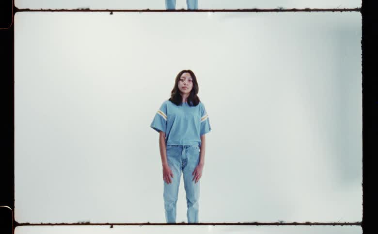 Woman with dark hair blue t shirt and jeans poses for the camera in the studio