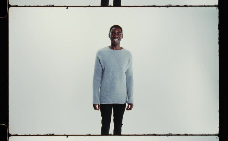 Man stands smiling against a pale background