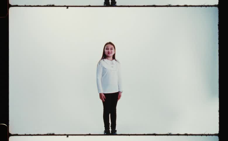 Girl stands in front of white and blue background smiling