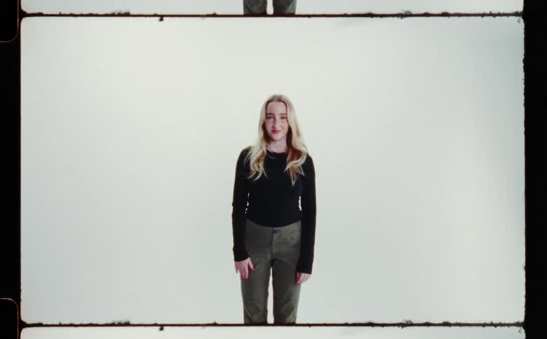 Blonde woman smiles while posing against pale background