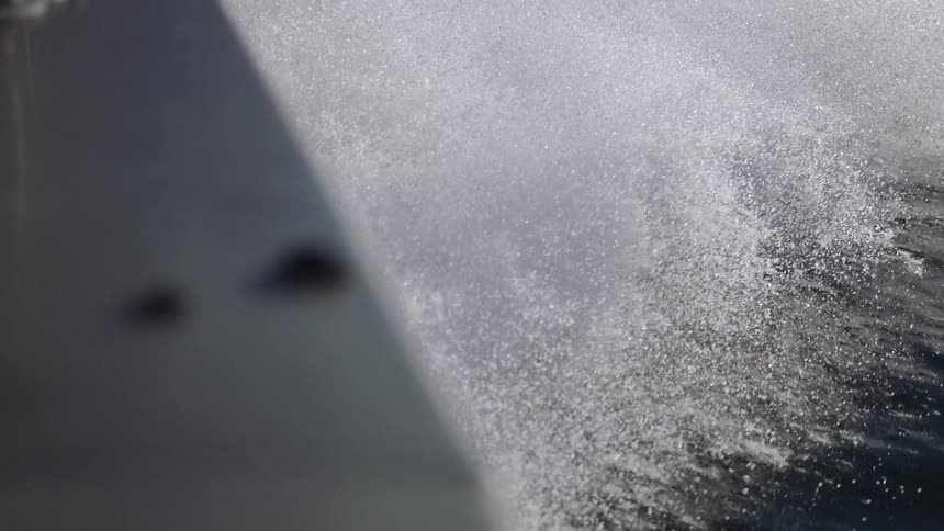 Waves splash behind a moving ship