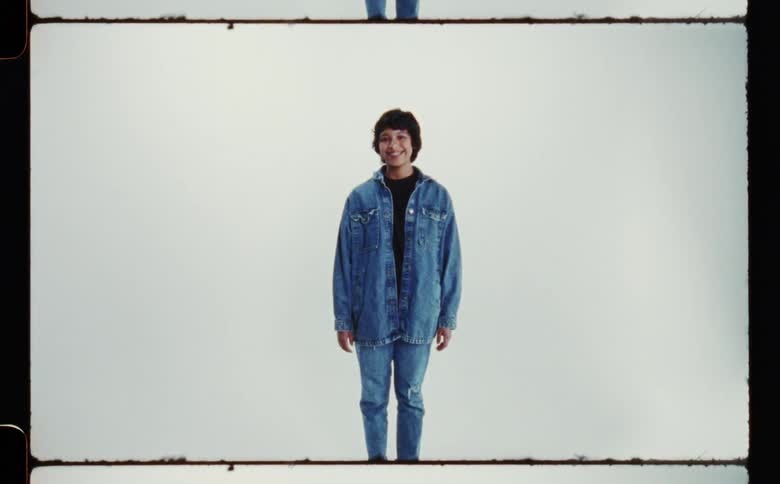Teenage boy standing wearing denim jacket and jeans smiling for camera