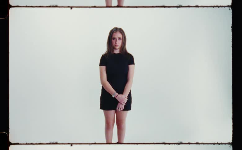 A girl stands solemnly while posing in a studio