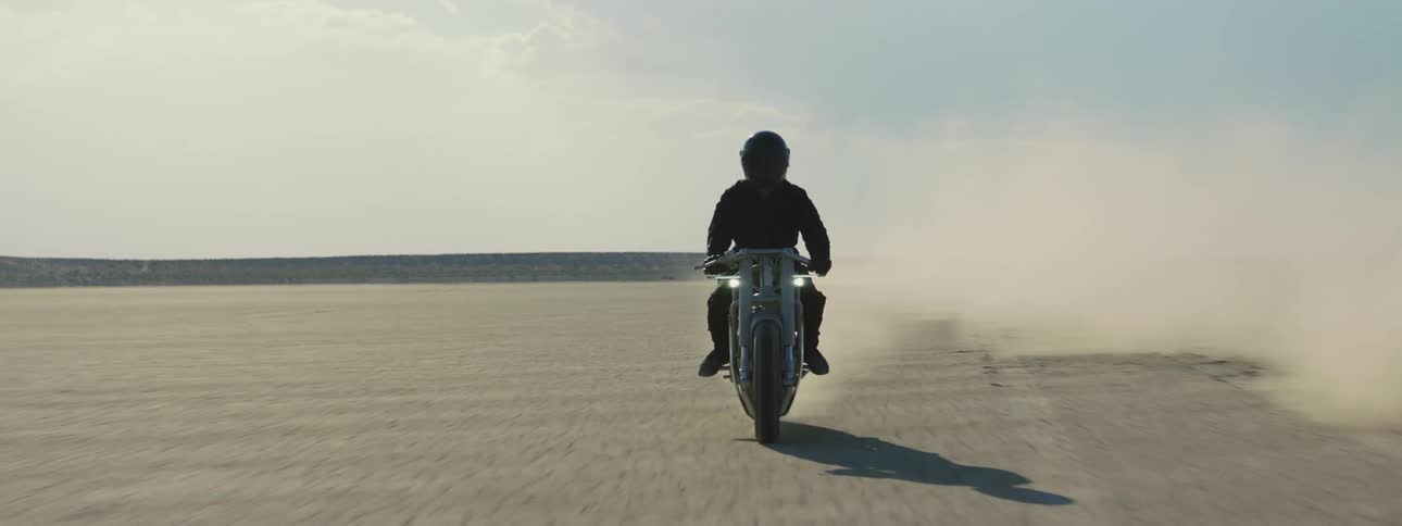 A person is driving a motorcycle through the desert