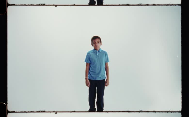 Boy with blue shirt and black pants poses for the camera in the studio