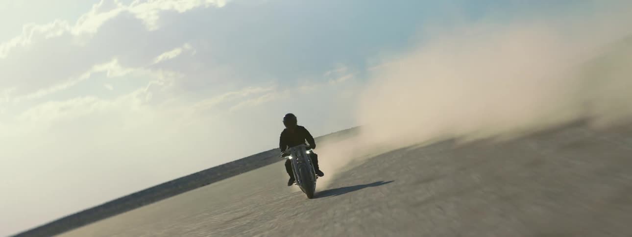 A person is driving a motorcycle through a desert area