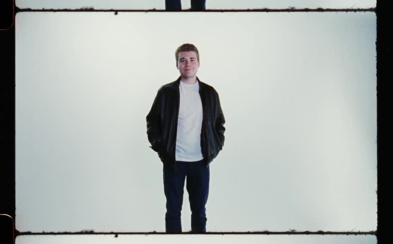A male is standing while wearing a jacket