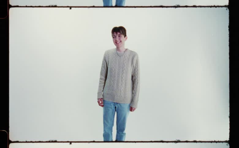 A teen male is smiling and standing in a room