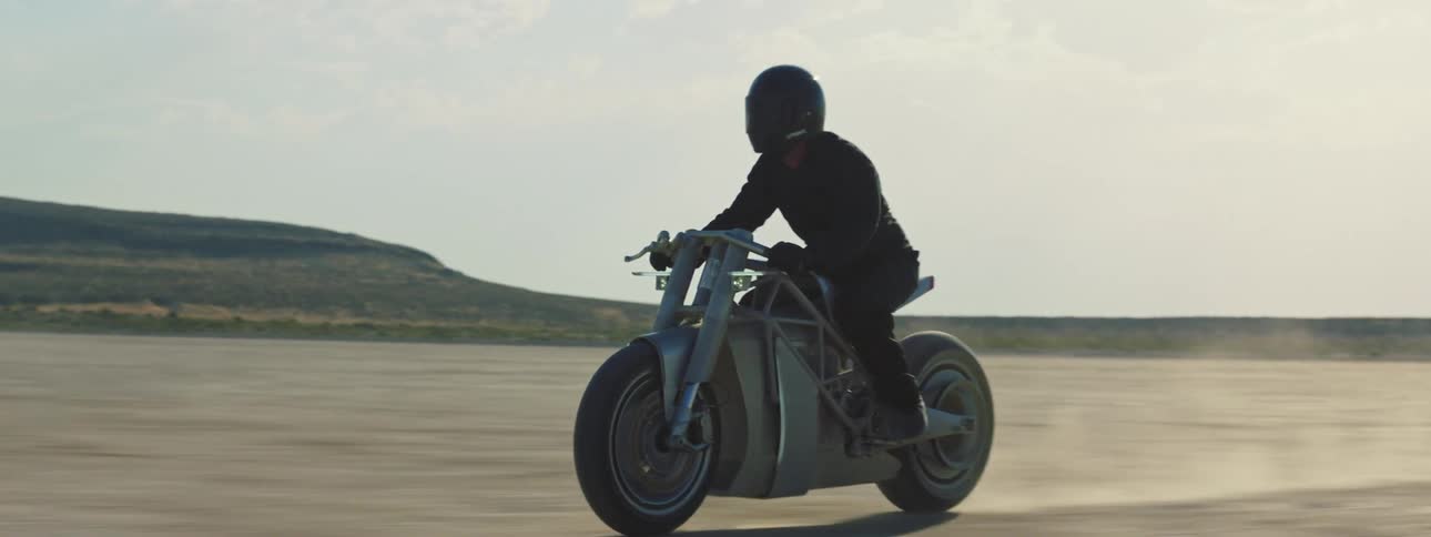 A person riding a motorcycle across a desert landscape
