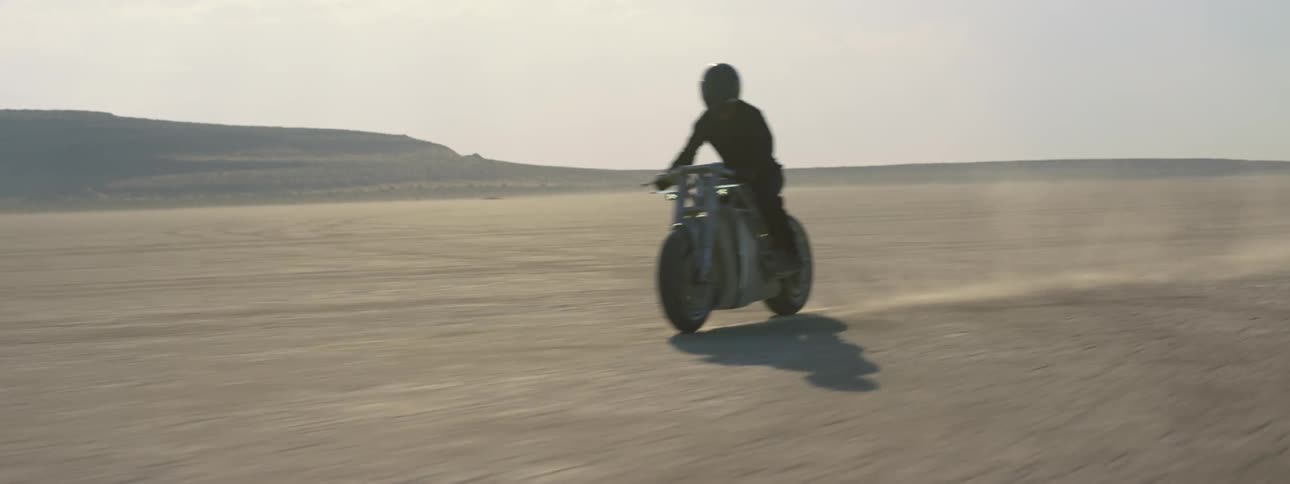 A person is driving a motorcycle through the desert