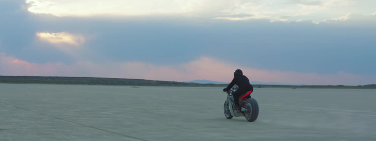 A person is driving a motorcycle through a desert landscape